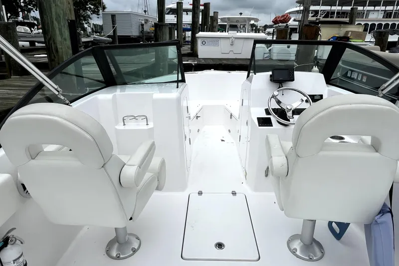 Slide: The Image of 2024 Aquasport 2200 Dual Console boat interior with white seating and steering wheel. - 6