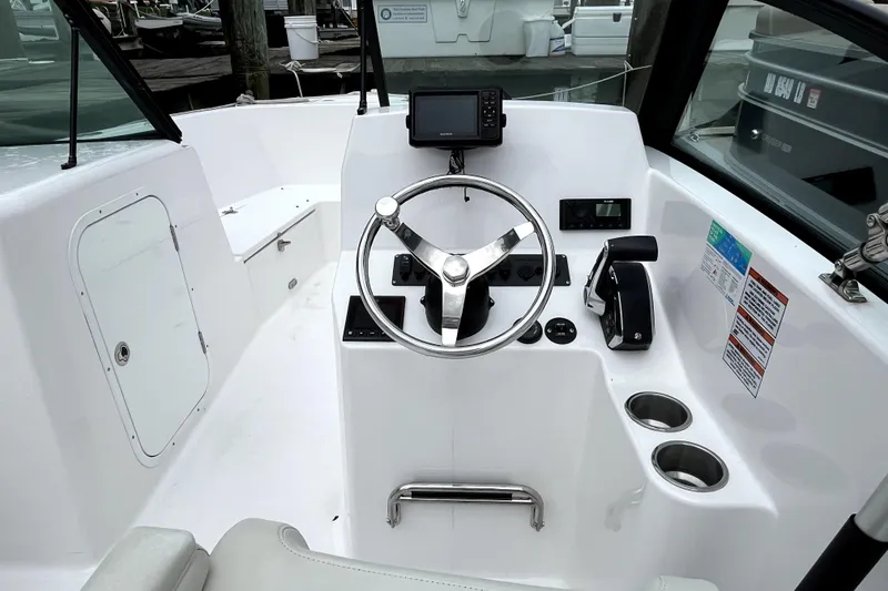 Slide: The Image of 2024 Aquasport 2200 Dual Console boat cockpit with steering wheel and controls. - 8