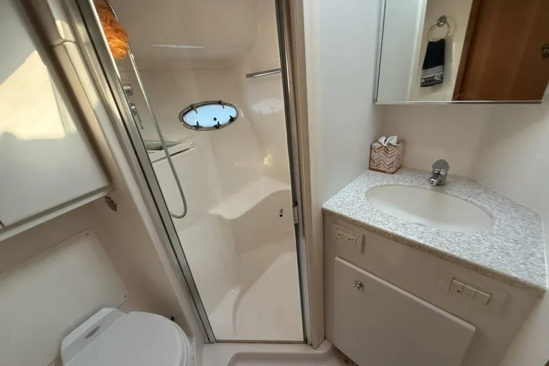 Slide: The Image of 2004 Tiara Yachts 4200 Open bathroom with shower, sink, and porthole window. - 13