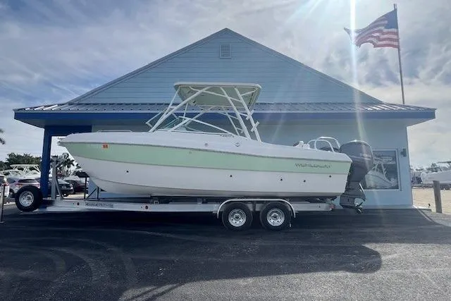 The Image of 2021 World Cat 230 SD boat on trailer, parked outside a blue building with American flag. - 1