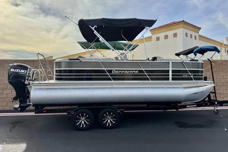 The Image of 2023 Berkshire 22RFX LE pontoon boat with Suzuki engine on trailer, parked outdoors. - 0