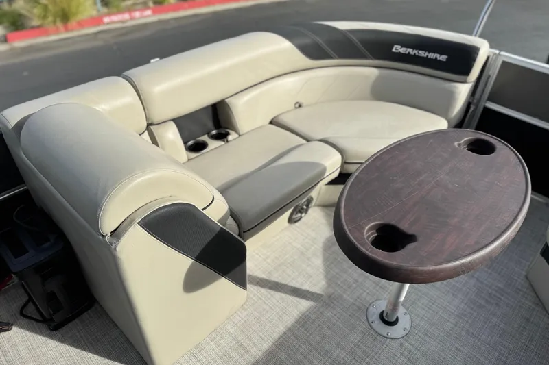 Slide: The Image of 2023 Berkshire 22RFX LE boat interior with beige seating and wooden table. - 17