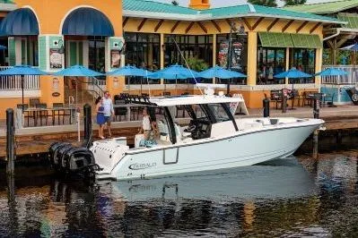 Slide: The Image of 2026 Robalo R360 Center Console boat docked near a colorful waterfront restaurant. - 4