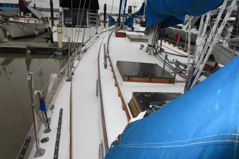 Slide: The Image of 1977 Valiant 40 sailboat docked, featuring blue sails and wooden deck details. - 12