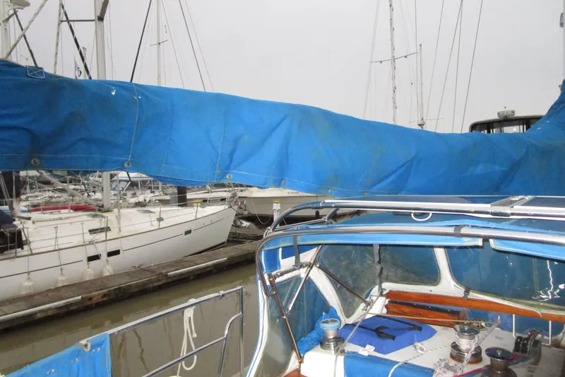 Slide: The Image of 1977 Valiant 40 sailboat with blue cover docked at marina. - 14