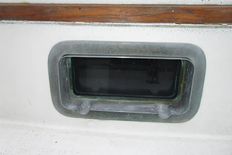 Slide: The Image of 1977 Valiant 40 boat porthole with wooden trim and metal frame. - 16