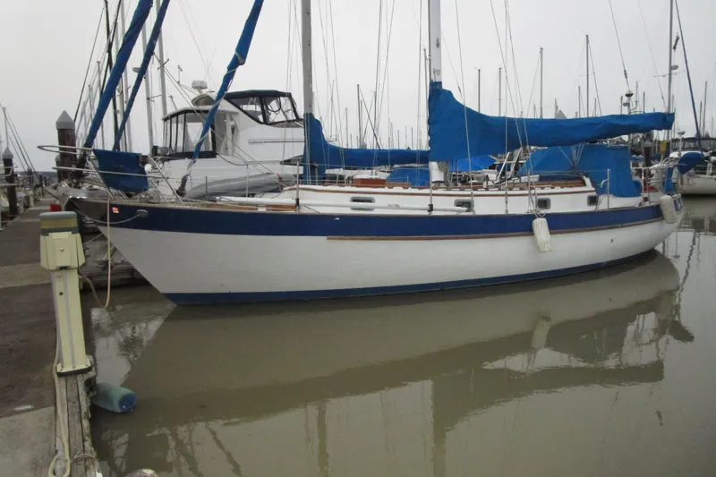 Slide: The Image of 1977 Valiant 40 sailboat docked in a marina with blue covers. - 2
