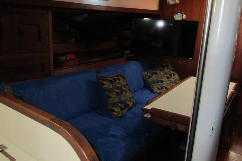 Slide: The Image of Interior of a 1977 Valiant 40 sailboat with blue seating and a mounted TV. - 29