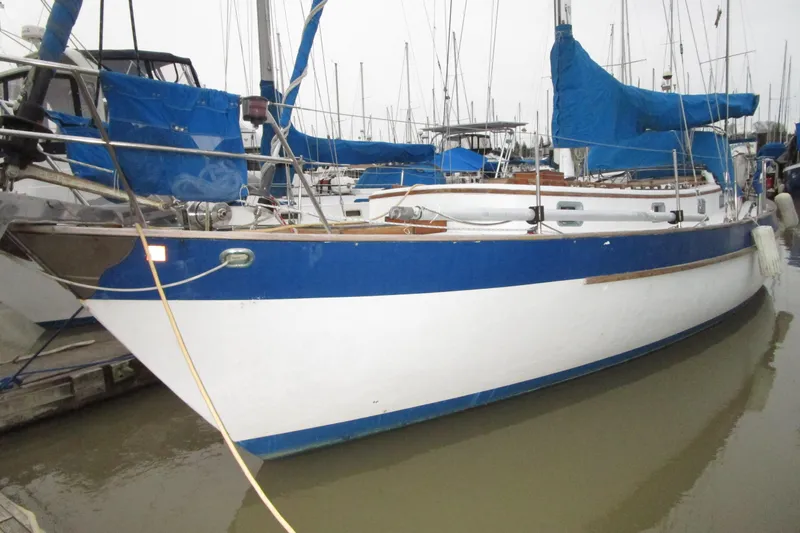 Slide: The Image of 1977 Valiant 40 sailboat docked, featuring blue and white hull with covered sails. - 3