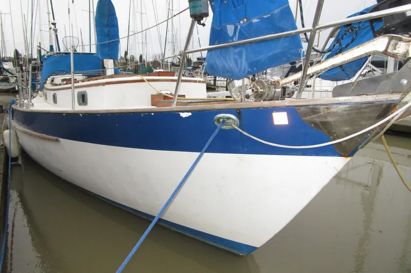 Slide: The Image of 1977 Valiant 40 sailboat docked, featuring blue and white hull with blue sails. - 4