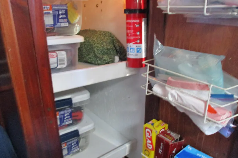 Slide: The Image of 1977 Valiant 40 boat storage with fire extinguisher, food containers, and kitchen supplies. - 49