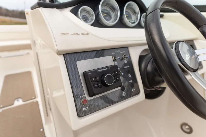 Slide: The Image of 2014 Sea Ray 240 Sundeck Outboard dashboard with steering wheel and control panel. - 13