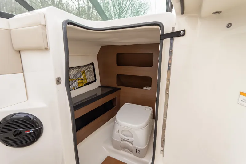 Slide: The Image of 2014 Sea Ray 240 Sundeck Outboard interior with compact marine toilet and storage. - 16