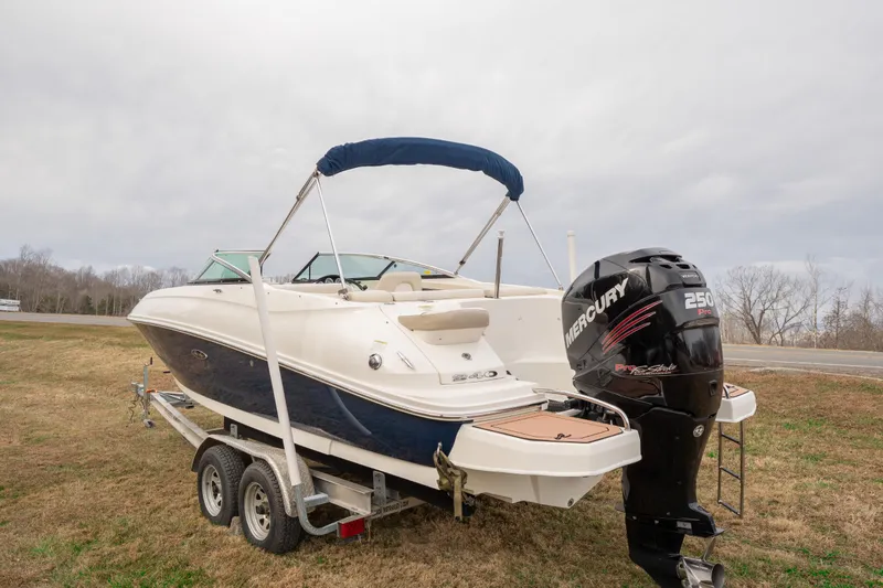 Slide: The Image of 2014 Sea Ray 240 Sundeck Outboard on trailer with Mercury engine, parked on grass. - 2
