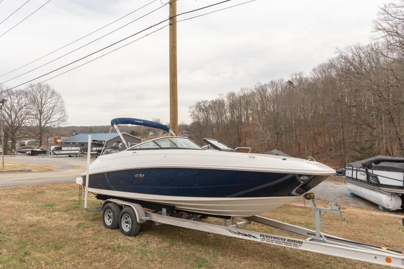 Slide: The Image of 2014 Sea Ray 240 Sundeck Outboard on trailer, parked outdoors near trees. - 3