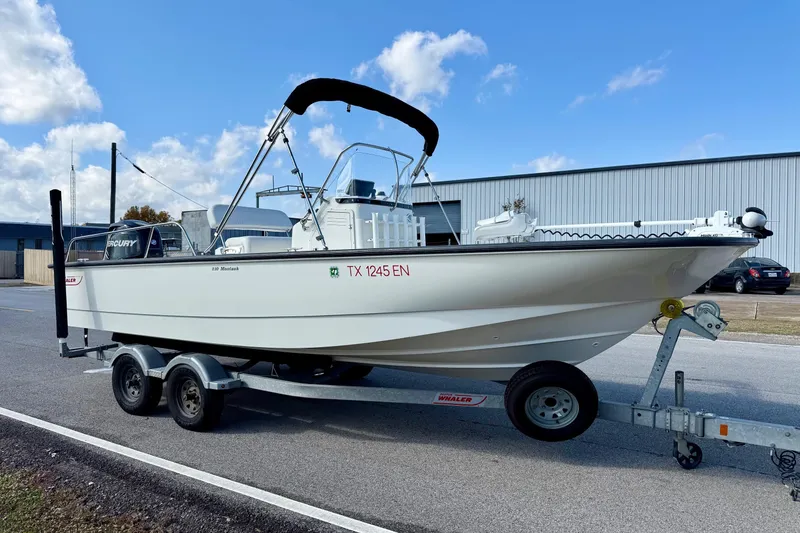 Slide: The Image of 2017 Boston Whaler 210 Montauk boat on trailer, parked outdoors under blue sky. - 5