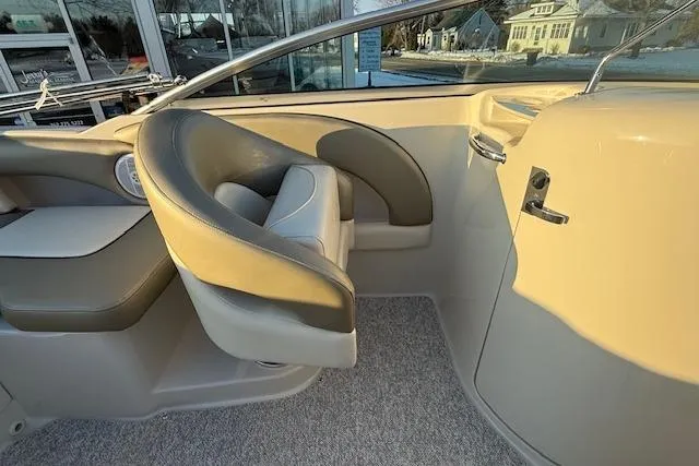 Slide: The Image of 2005 Sea Ray 220 Sundeck interior with beige seating and steering area. - 10