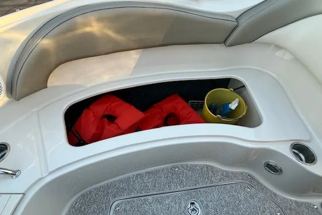 Slide: The Image of 2005 Sea Ray 220 Sundeck storage area with life jackets and cleaning supplies. - 18
