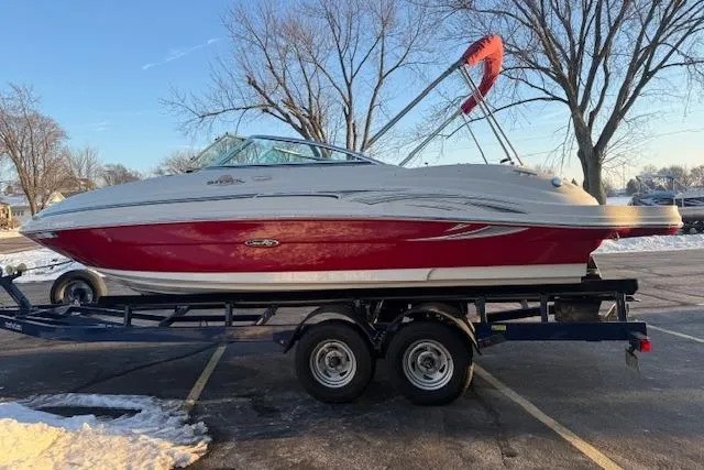 Slide: The Image of 2005 Sea Ray 220 Sundeck boat on trailer, red and white, parked in snowy lot. - 3