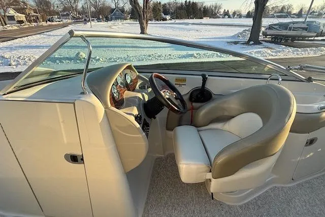 Slide: The Image of 2005 Sea Ray 220 Sundeck interior with steering wheel and seating, parked in snowy landscape. - 5