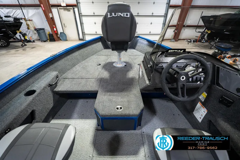 Slide: The Image of 2026 Lund 1675 Adventure SS boat interior with steering wheel and seating in a showroom. - 15