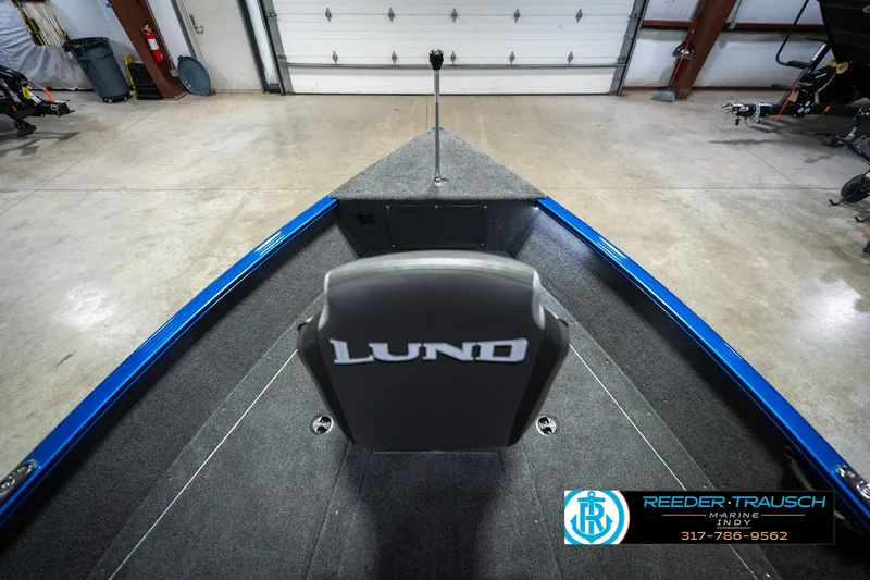 Slide: The Image of 2026 Lund 1675 Adventure SS boat interior with gray seating and blue trim in a showroom. - 16