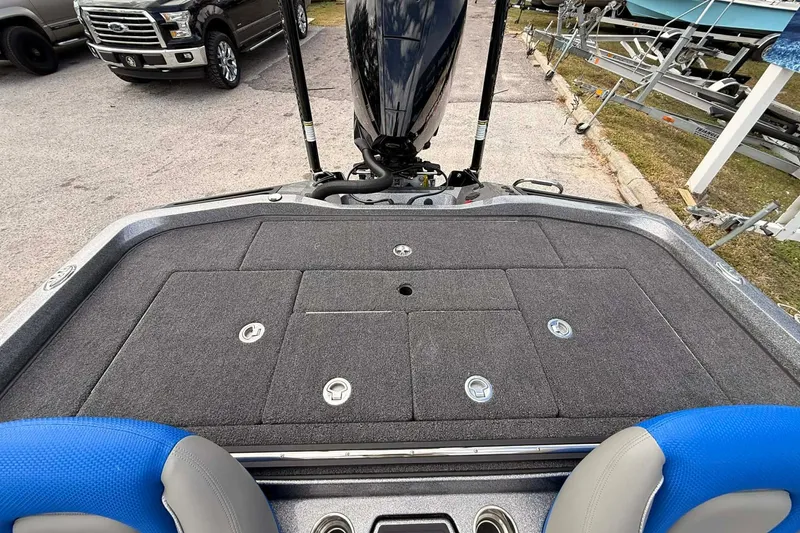 Slide: The Image of 2026 Ranger Z518 boat deck with storage compartments and motor, parked near vehicles. - 9