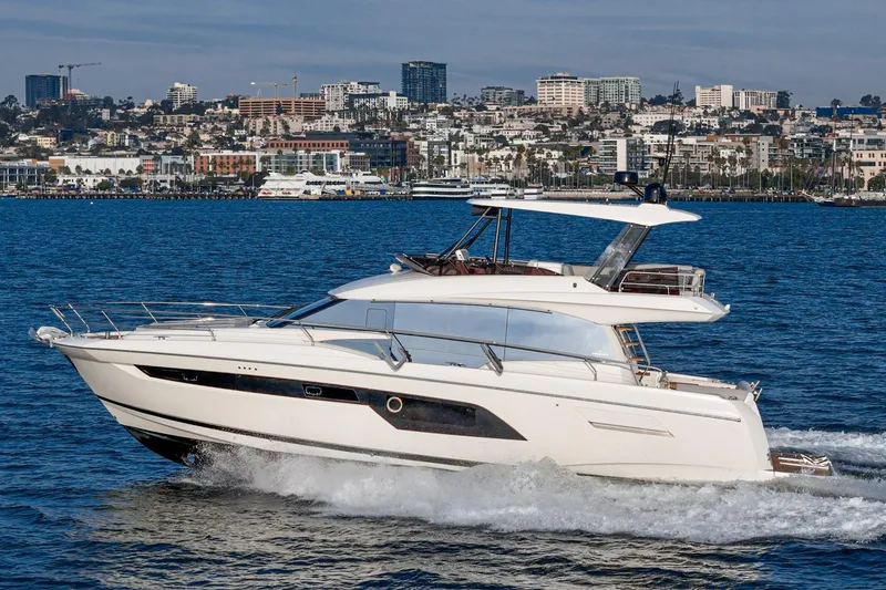 Slide: The Image of 2023 Prestige 520 yacht cruising on blue water with city skyline backdrop. - 13