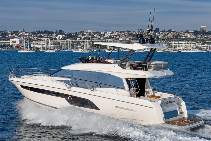 Slide: The Image of 2023 Prestige 520 yacht cruising on the ocean near a coastal city. - 14