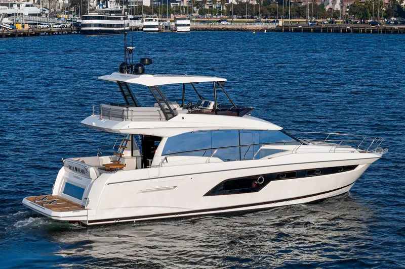 Slide: The Image of 2023 Prestige 520 yacht cruising on blue water near a marina. - 20