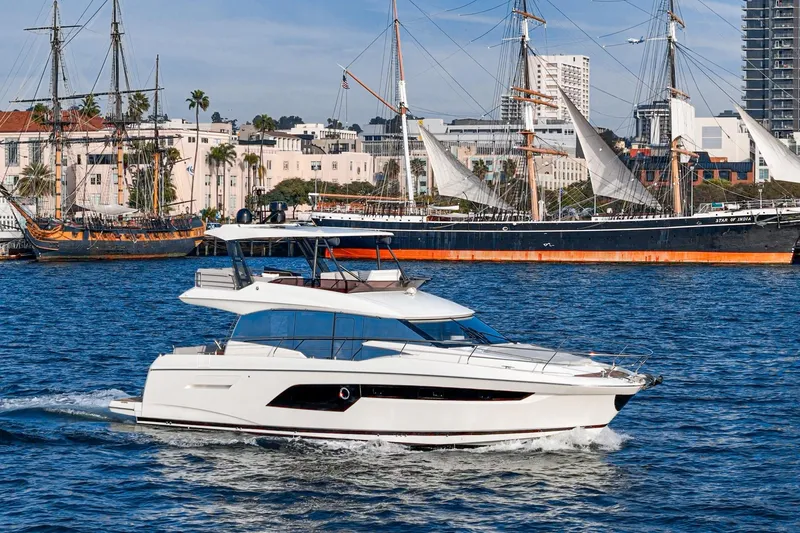 Slide: The Image of 2023 Prestige 520 yacht cruising near historic sailing ships in a vibrant harbor. - 21
