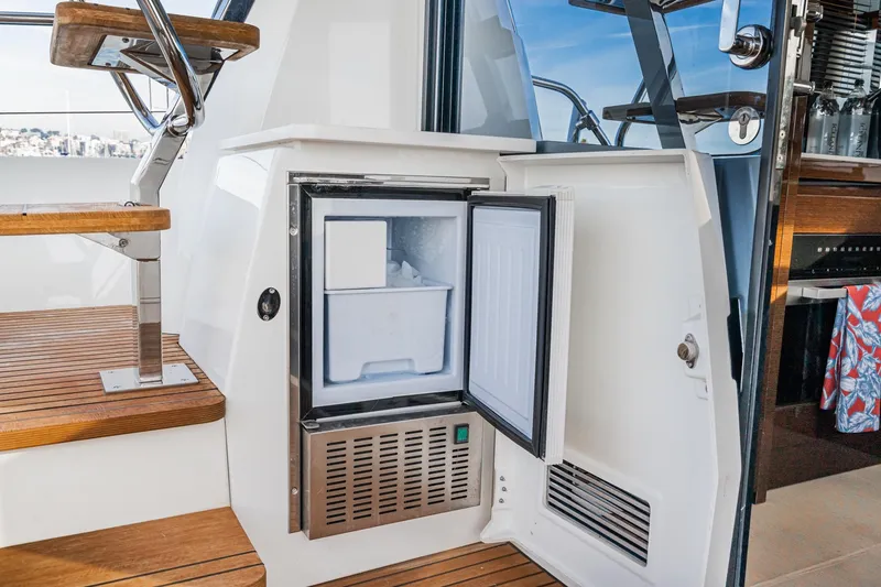 Slide: The Image of Open mini fridge on 2023 Prestige 520 yacht, near wooden stairs and glass door. - 37