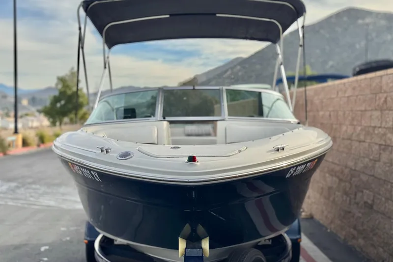 Slide: The Image of 2006 Sea Ray 220 Select boat with canopy, parked on a trailer, mountain backdrop. - 2