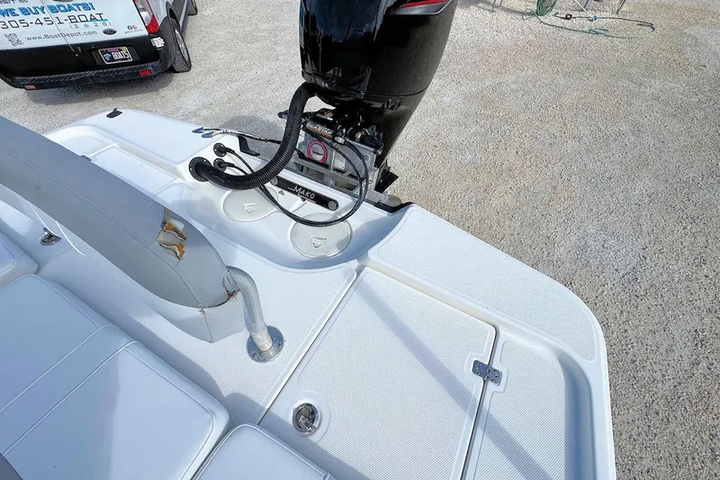 Slide: The Image of 2019 Mako 21 LTS boat with outboard motor and seating area, parked on gravel. - 7
