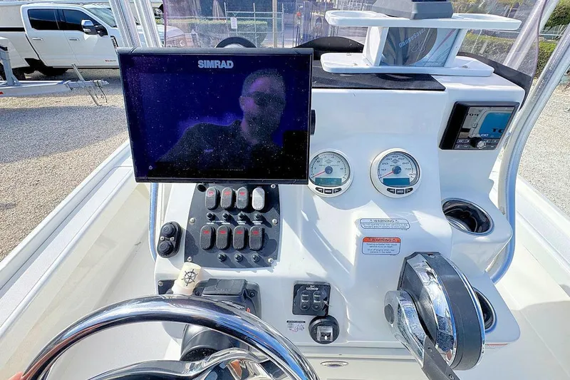Slide: The Image of 2019 Mako 21 LTS boat dashboard with Simrad display and control gauges. - 8