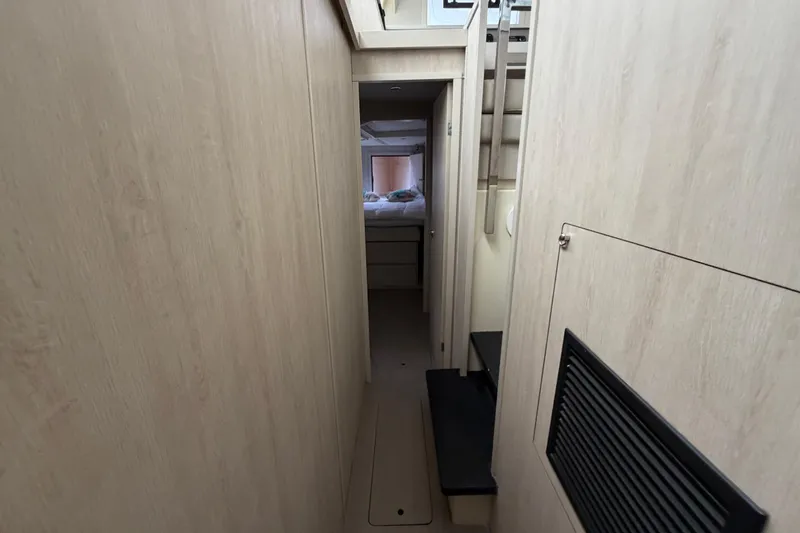 Slide: The Image of Narrow hallway inside 2016 Leopard 51 Powercat, featuring light wood paneling and steps leading to cabin. - 26