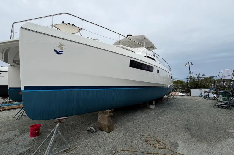 Slide: The Image of 2016 Leopard 51 Powercat yacht on dry dock, white hull with blue trim, overcast sky. - 29