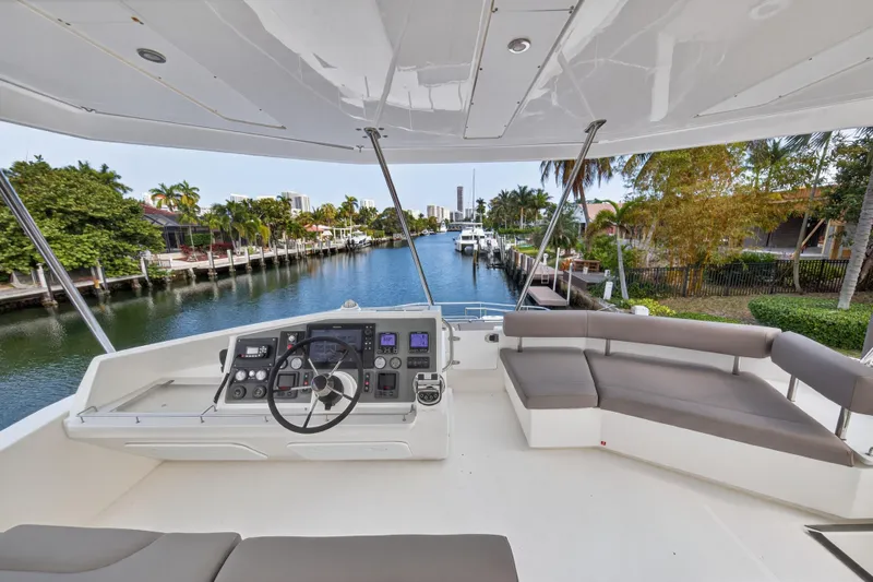 Slide: The Image of Flybridge view of 2016 Leopard 51 Powercat, featuring helm and seating, overlooking a scenic canal. - 33