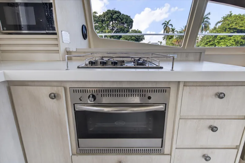 Slide: The Image of Kitchen area of 2016 Leopard 51 Powercat with stove and oven, featuring scenic window view. - 77