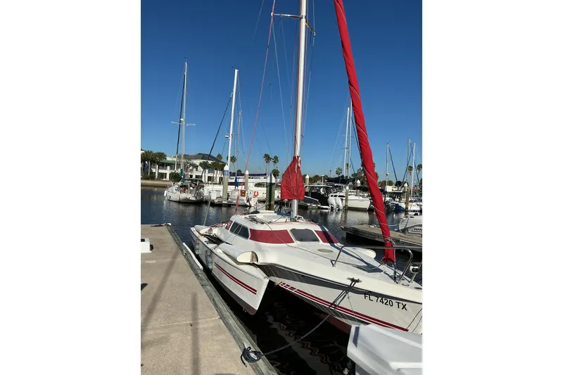 Slide: The Image of 1992 Dragonfly 800 Swing Wing sailboat docked with red sails in a marina. - 48