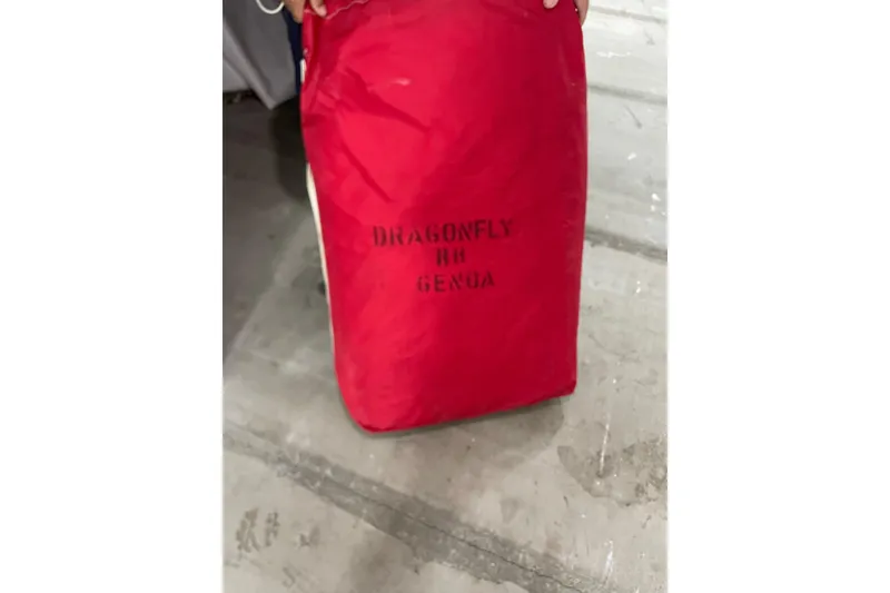 Slide: The Image of Red sail bag labeled "Dragonfly RH Genoa" on a concrete floor. - 63