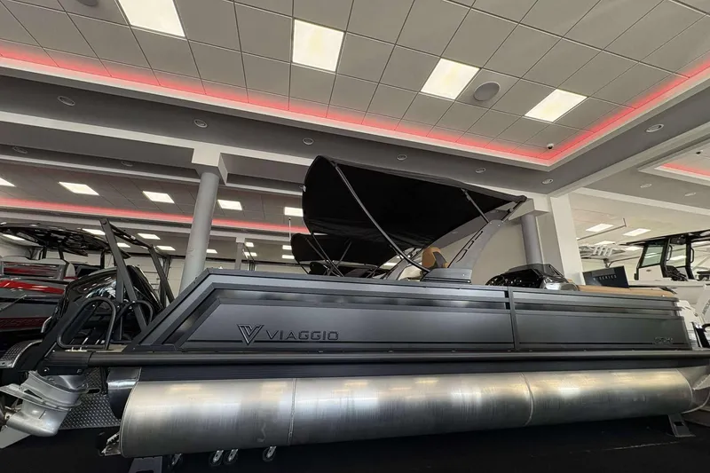 Slide: The Image of 2026 Viaggio Z24B pontoon boat displayed in a showroom with modern ceiling lights. - 2