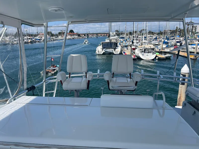 Slide: The Image of Flybridge view of 2000 Hatteras 60 yacht in a marina with boats. - 12