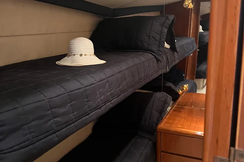 Slide: The Image of Bunk beds with black bedding in a 2000 Hatteras 60 yacht cabin, featuring a white hat. - 9