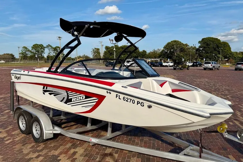 Slide: The Image of 2012 Tigé R20 boat on trailer, white with red accents, parked outdoors. - 1
