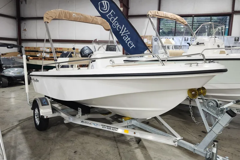 The Image of 2024 Edgewater 158CS boat on trailer in showroom, featuring sleek design and beige canopy. - 0