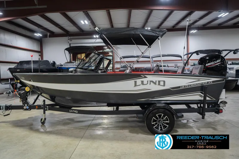 Slide: The Image of 2026 Lund 1875 Crossover XS boat in showroom, featuring sleek design and spacious interior. - 11