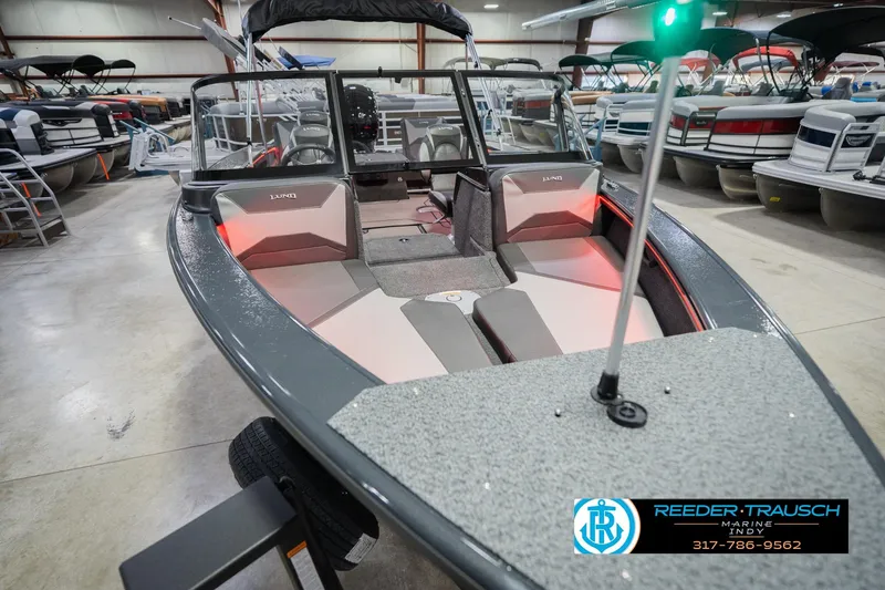 Slide: The Image of 2026 Lund 1875 Crossover XS boat interior with seating and storage in a garage setting. - 13