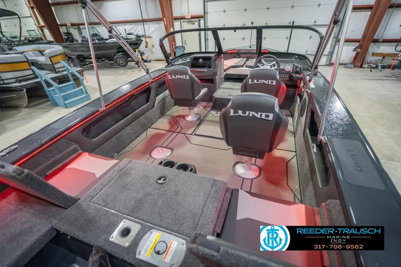 Slide: The Image of 2026 Lund 1875 Crossover XS boat interior with seating and steering wheel in a showroom. - 14