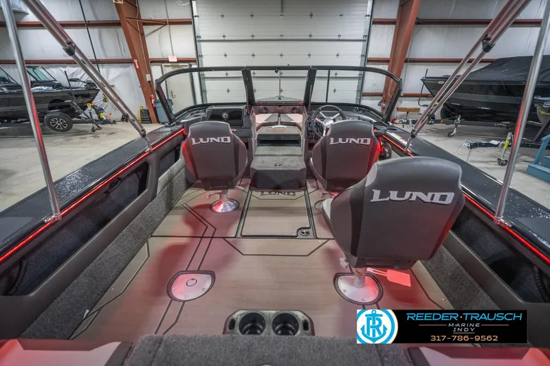 Slide: The Image of 2026 Lund 1875 Crossover XS boat interior with red LED lighting in a garage setting. - 16